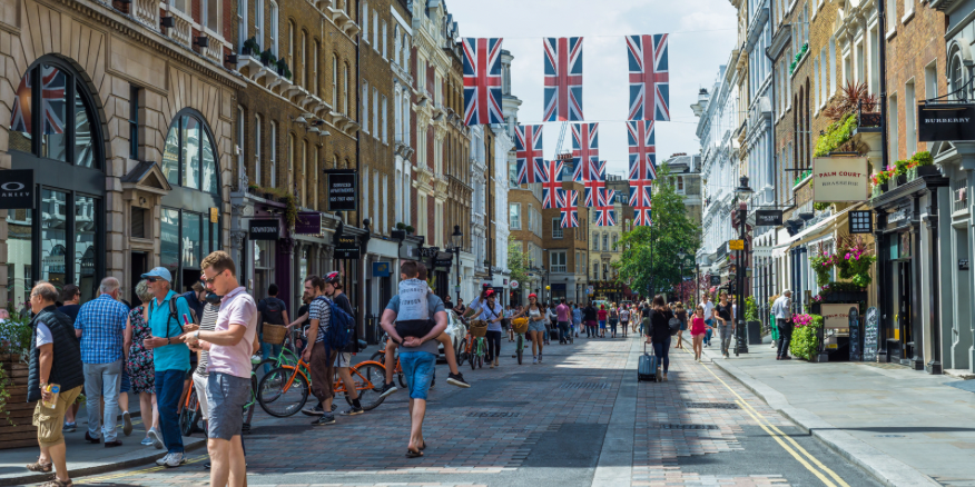 Photo of central London in a vibrant area, with people walking down the street and shops on the side of the road